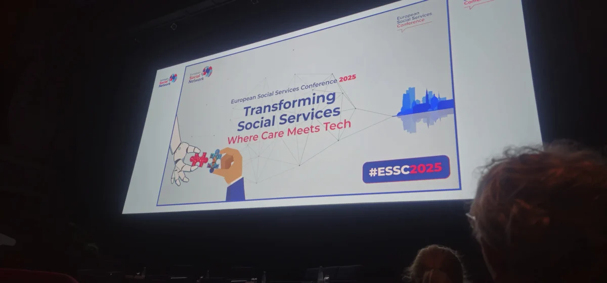 Uvodni zaslon konference ESSC 2025 z naslovom “Transforming Social Services – Where Care Meets Tech” v temni dvorani.