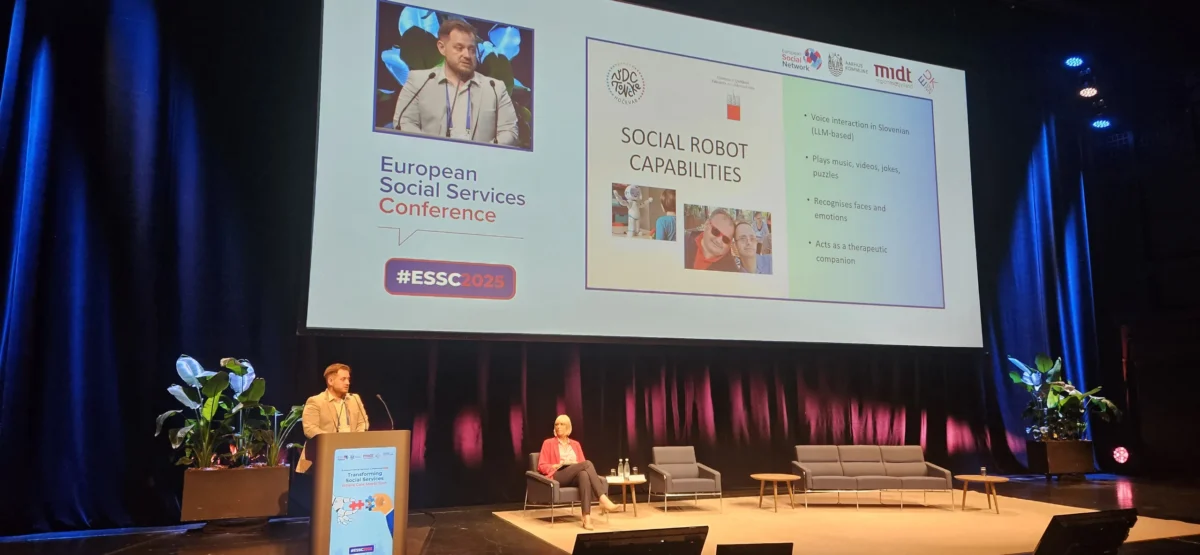 Predstavitev projekta “Social Robot Capabilities” na ESSC 2025: govorec stoji ob odru, na zaslonu pa so predstavljene funkcije terapevtskega robota za osebe z intelektualnimi ovirami.