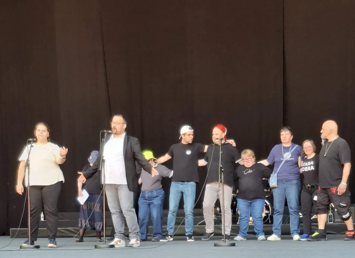 Dva uporabnika pojeta duet na odru, ostali nastopajoči stojijo v ozadju.