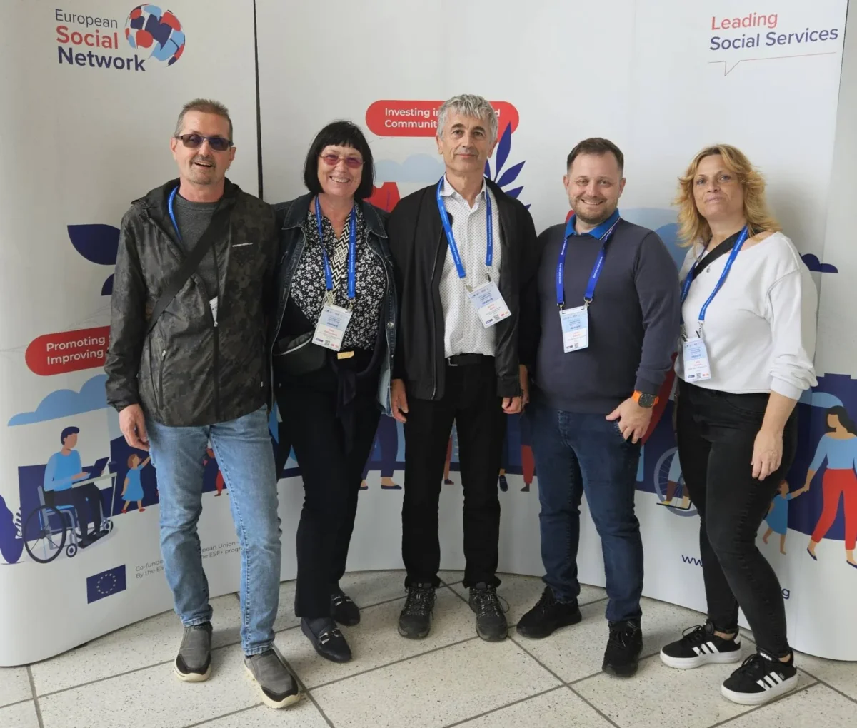 Skupinska fotografija udeležencev iz Slovenije na konferenci ESSC 2025 pred uradno steno z logotipi European Social Network in dogodka.