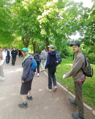 Udeleženci hodijo po senčni poti skozi park v okviru pohoda Pot ob žici.
