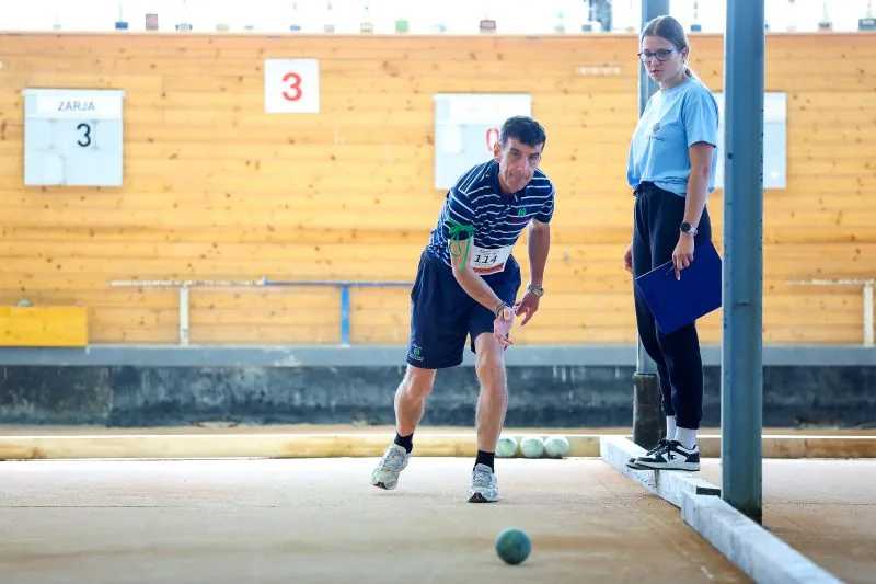 Tekmovalec meče balinarsko kroglo med tekmovanjem.