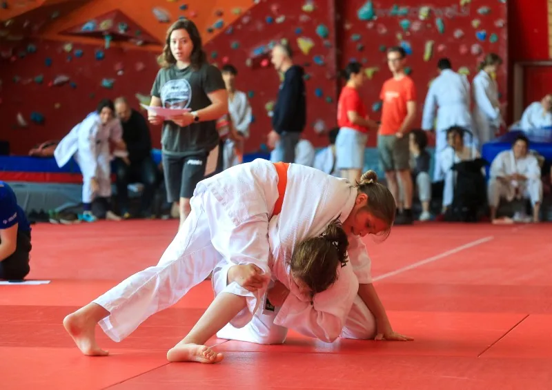 Tekmovalca izvajata judo prijem med tekmo na blazini.