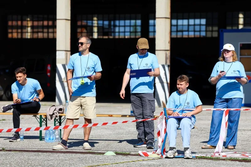 Ekipa sodnikov na kolesarski dirki stoji in sedi ob strani ter beleži rezultate
