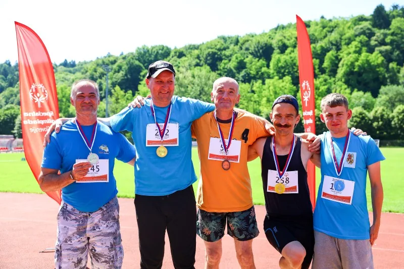 Pet tekmovalcev z medaljami pozira fotografu