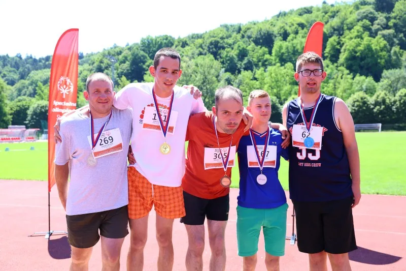 Skupina tekmovalcev z medaljami okoli vratu se objemajo okoli ramen