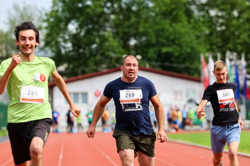 Trije tekmovalci vzporedno tečejo na stadionu