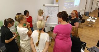 Udeleženci strokovnega posveta med skupinskim delom ob tabli, na kateri zapisujejo predloge za izboljšanje kakovosti storitev.