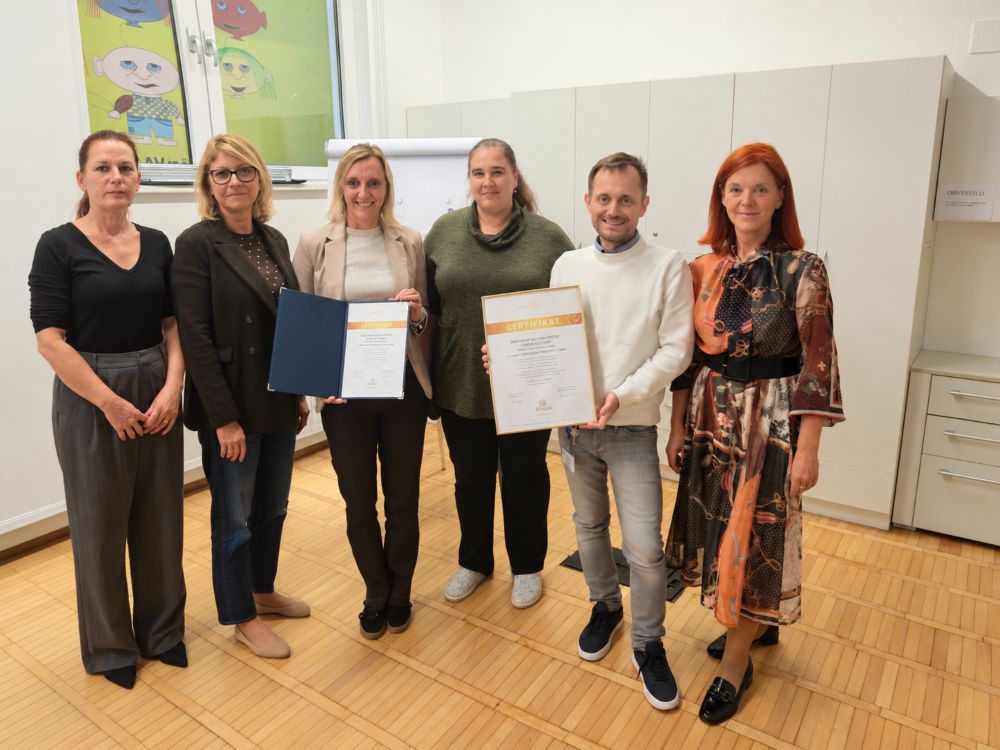 Šest predstavnikov VDC-ja, dva držita v rokah tiskani certifikat E-Qualin.