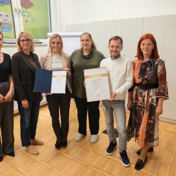 Šest predstavnikov VDC-ja, dva držita v rokah tiskani certifikat E-Qualin.
