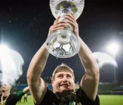 Varovanec ponosno dviguje pokal na nogometnem stadionu