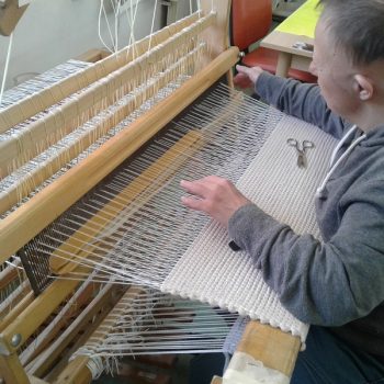 Veliko tkalno šivanko potisnemo skozi nastalo režo niti. Režo naredimo z pedalkami.