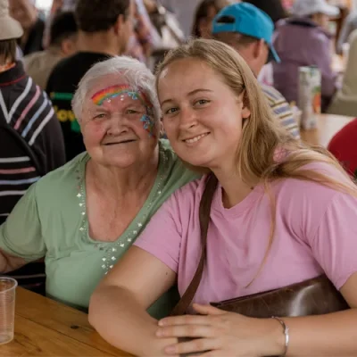 Naša varovanka in njena skrbnica uživata za mizo. Varovanka je namaskirana in ima nasmeh do ušes.